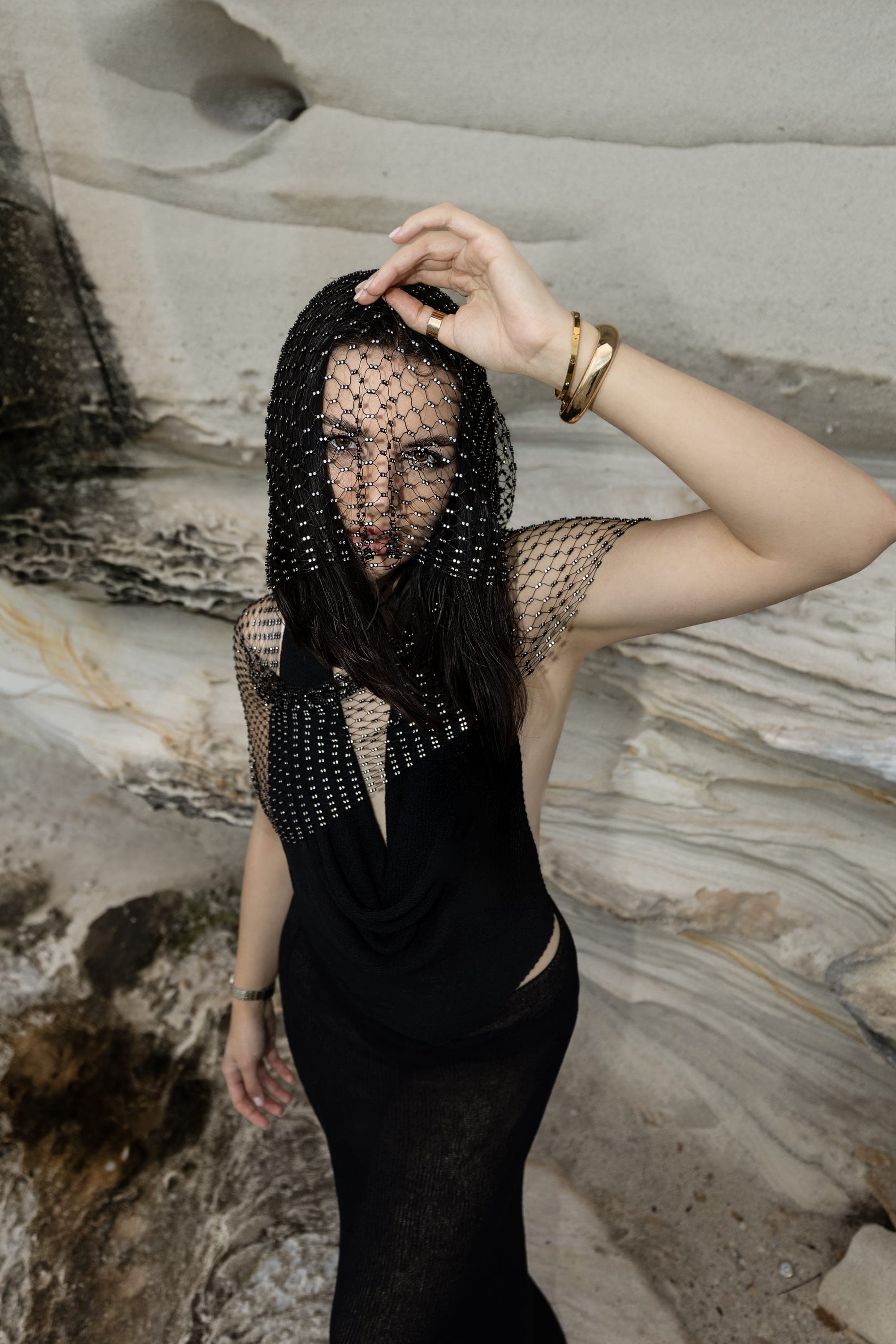 Model in a black beaded veil and gown on sandstone rocks, high-fashion editorial in Sydney