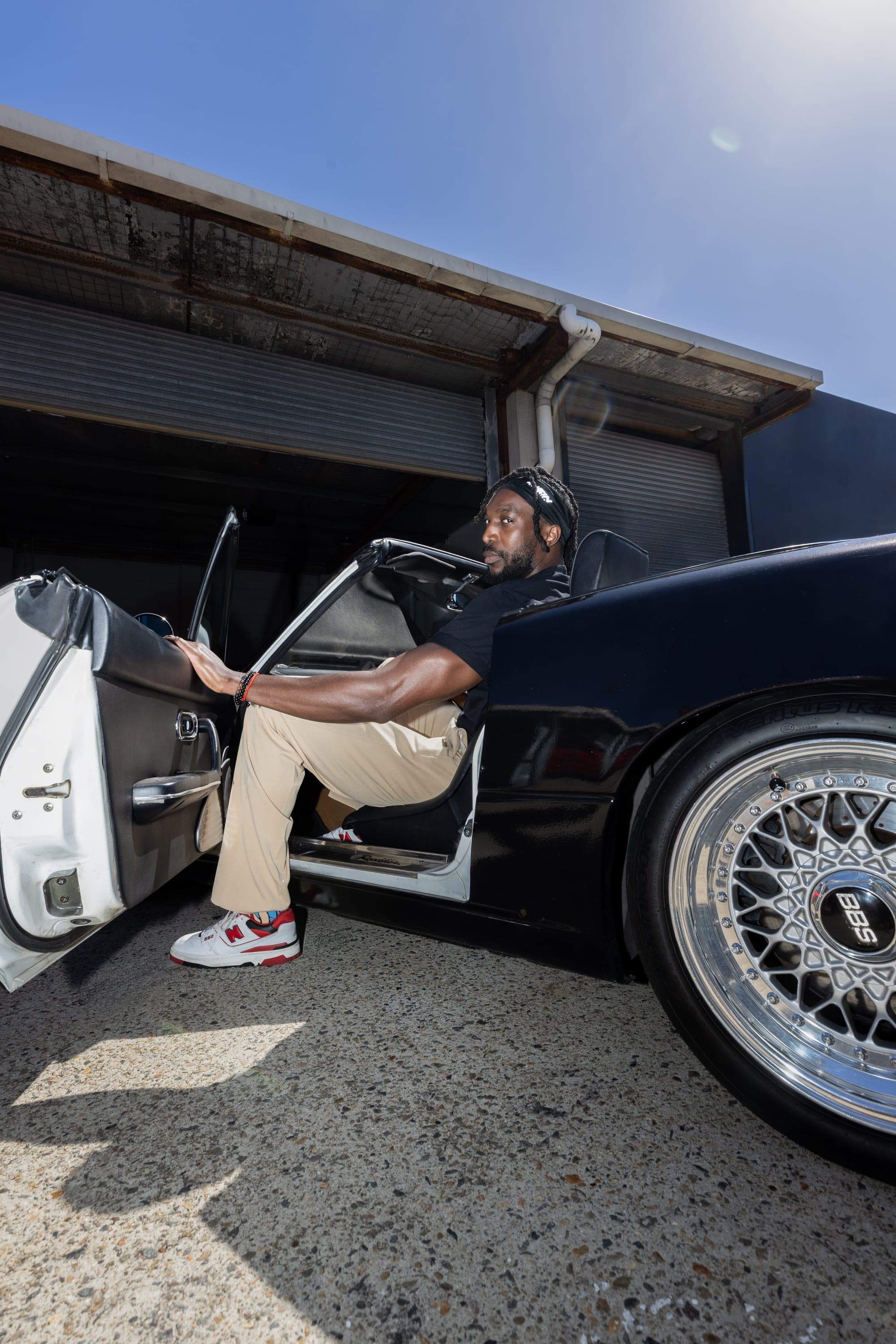 Man in a black shirt getting into a classic convertible sports car, Sydney street fashion shoot