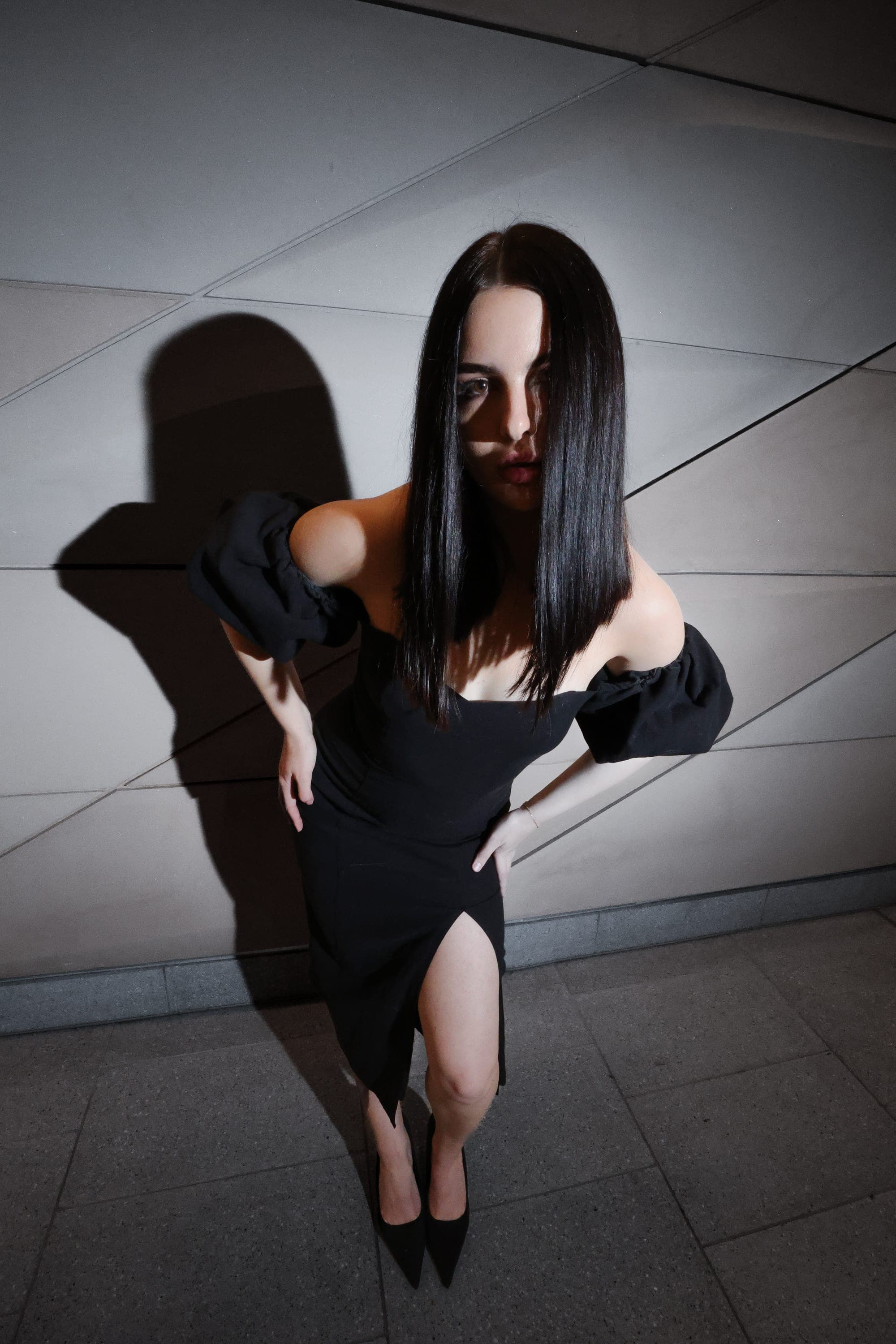 Model in a black off-shoulder gown against an angular tunnel wall, Sydney street fashion editorial