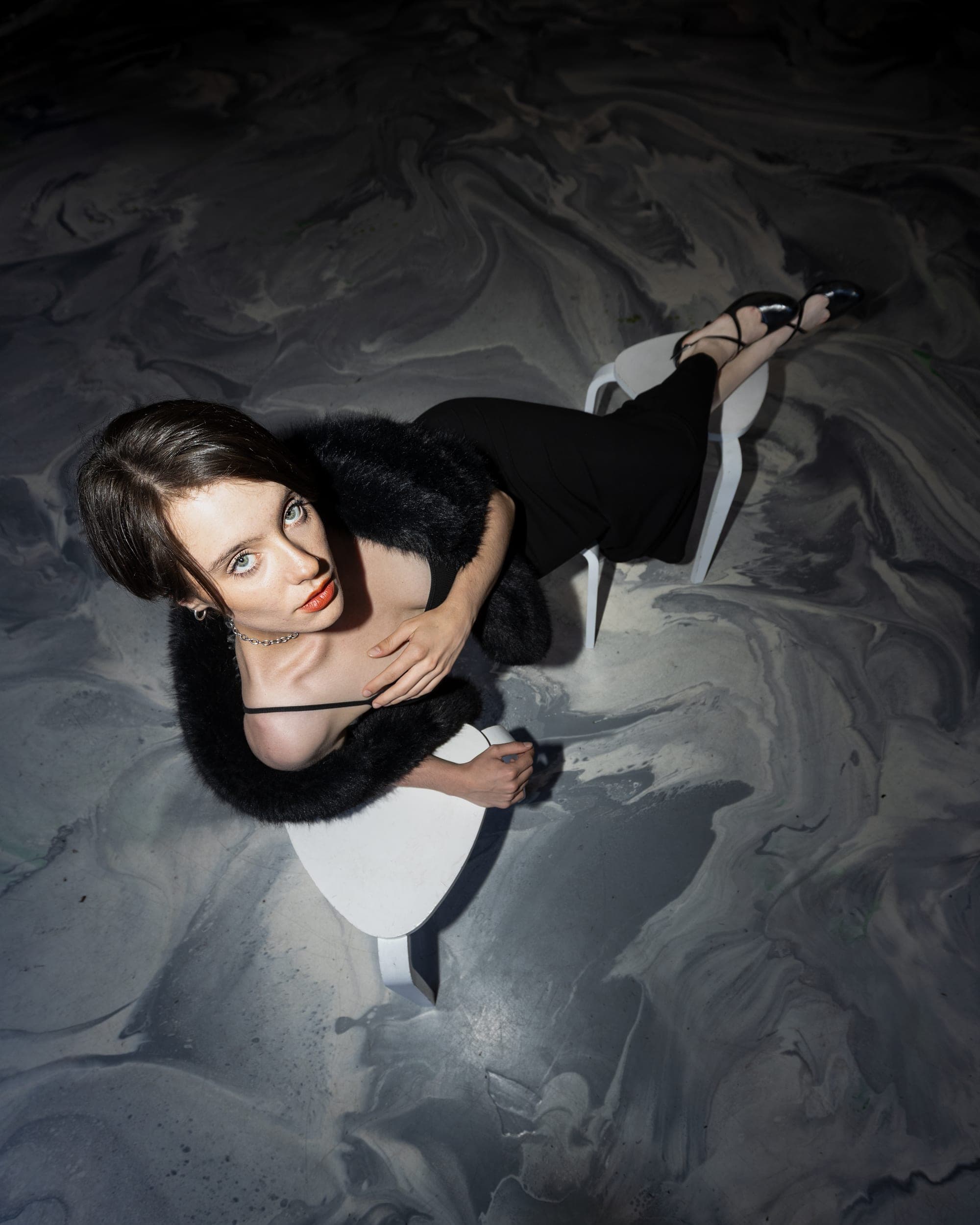 Overhead shot of a model in a faux fur stole on a marbled studio backdrop, editorial studio photography